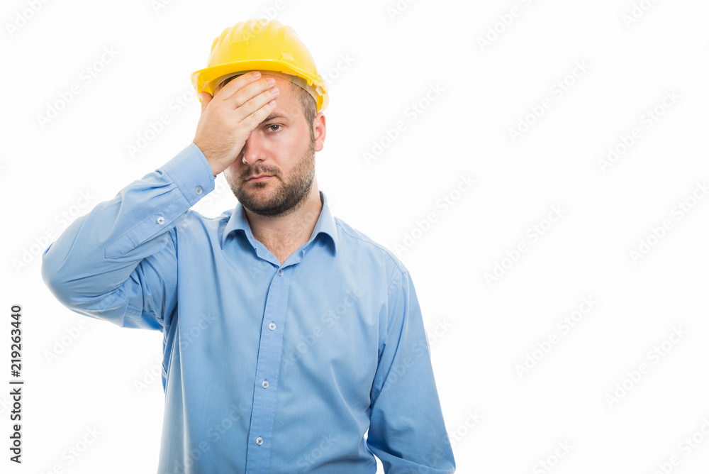 Young architect with yellow helmet showing headache gesture