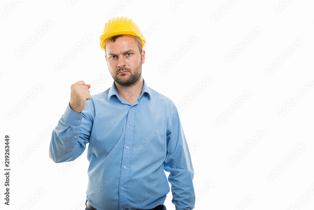 Young architect with yellow helmet showing angry fist gesture