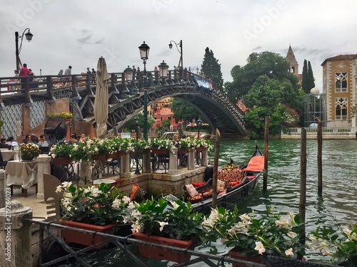 Beautiful bridge and flowers over a canal in venice itlay on a cloudy day with gondola 