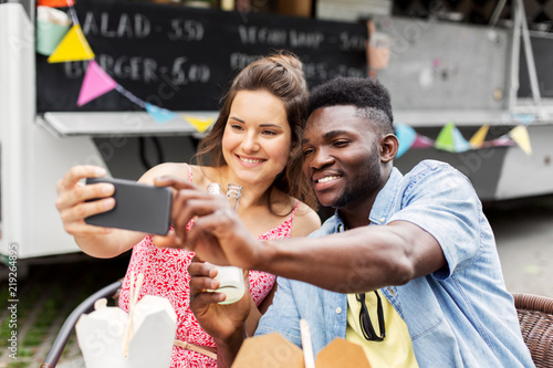 leisure, technology and people concept - happy mixed race couple taking selfie by smartphone at food truck © Syda Productions