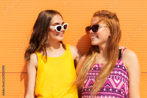 fashion  leisure and people concept - smiling teenage girls in summer clothes hugging outdoors