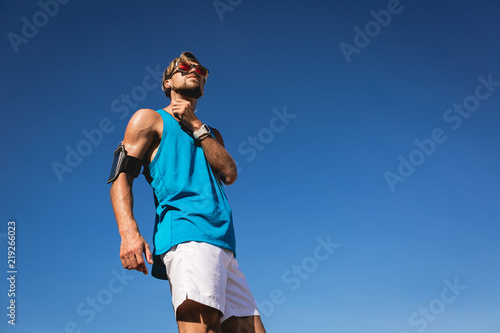 bottom view of sportsman in sunglasses with smartphone armband