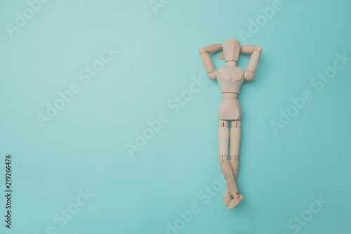 Wooden puppet points aside with its hand. Conceptual image about relax time. Minimal style.