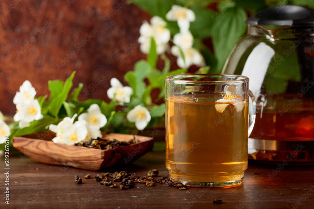 Green tea with jasmine in cup and teapot on old wooden table. Green tea with jasmine in cup and teapot on old wooden table.
