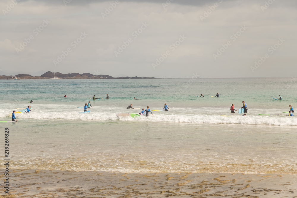 Surf school students in the waves of  Fuerteventura, Canary Islands, Spain.