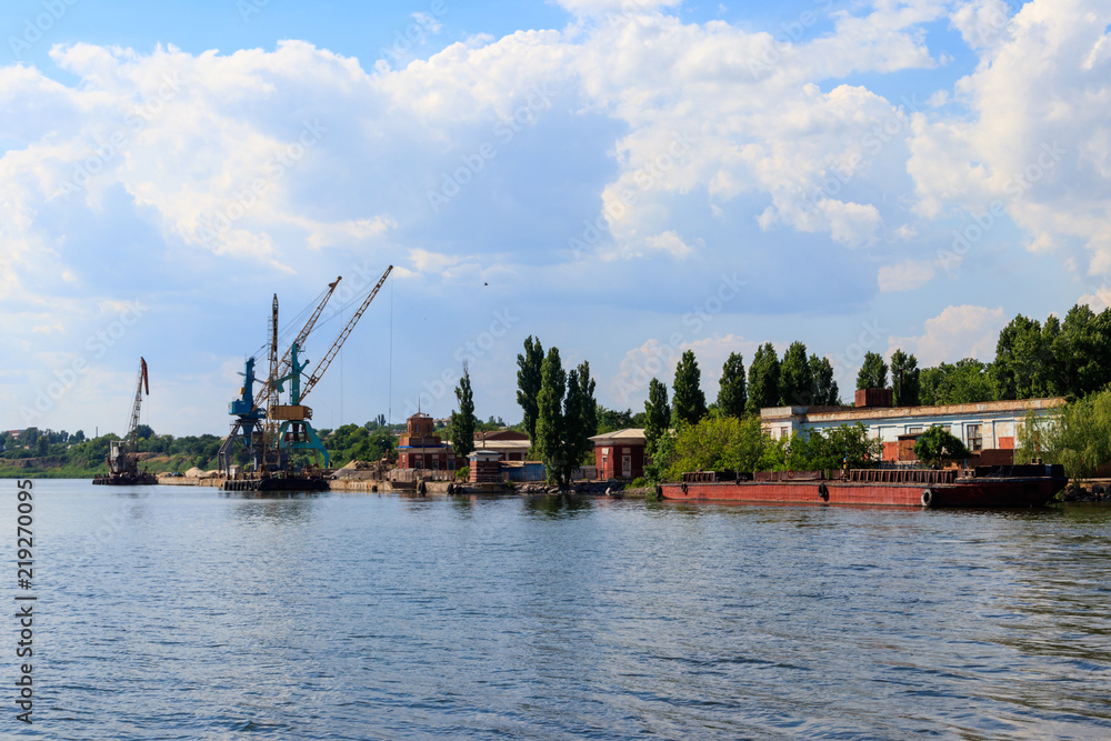 Heavy cranes in cargo port on the riverbank