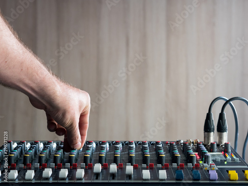 Mans hand adjusting buttons on audio mixer