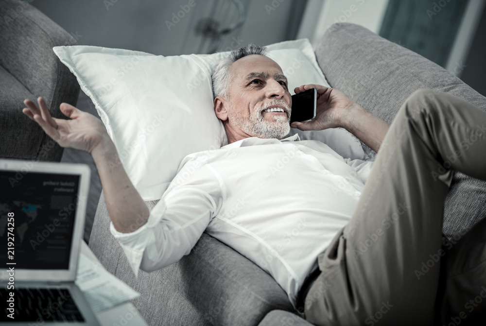 Fototapeta premium Pleasant talk. Happy mature male person having rest while talking per telephone