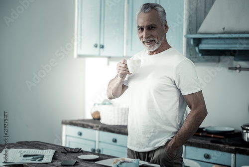 Happy to be here. Cheerful senior man smiling while standing in the kitchen