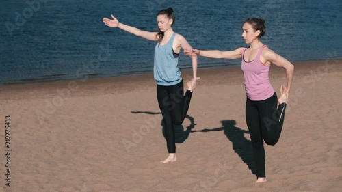 Two woman doing yoga on the beach by the river in the city. Beautiful view. photo