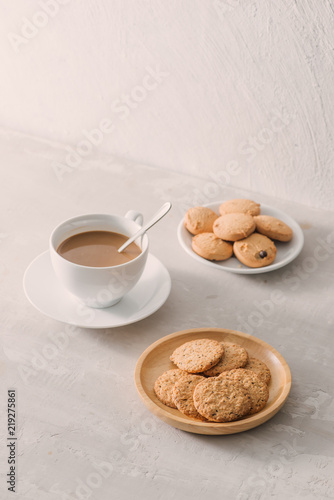 Cup of coffee with milk or cappuccino with cookies on light stone background. Drink with caffeine or cocoa with milk. Coffee break concept.