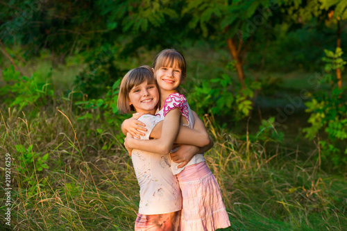 Two adorable little sisters laughing and hugging on sunny day in summer park © Svetlana