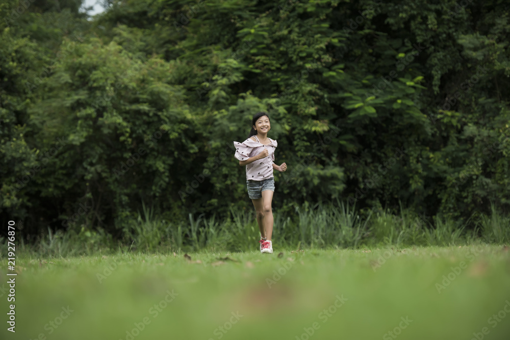 Happy cute little girl running on the grass in the park