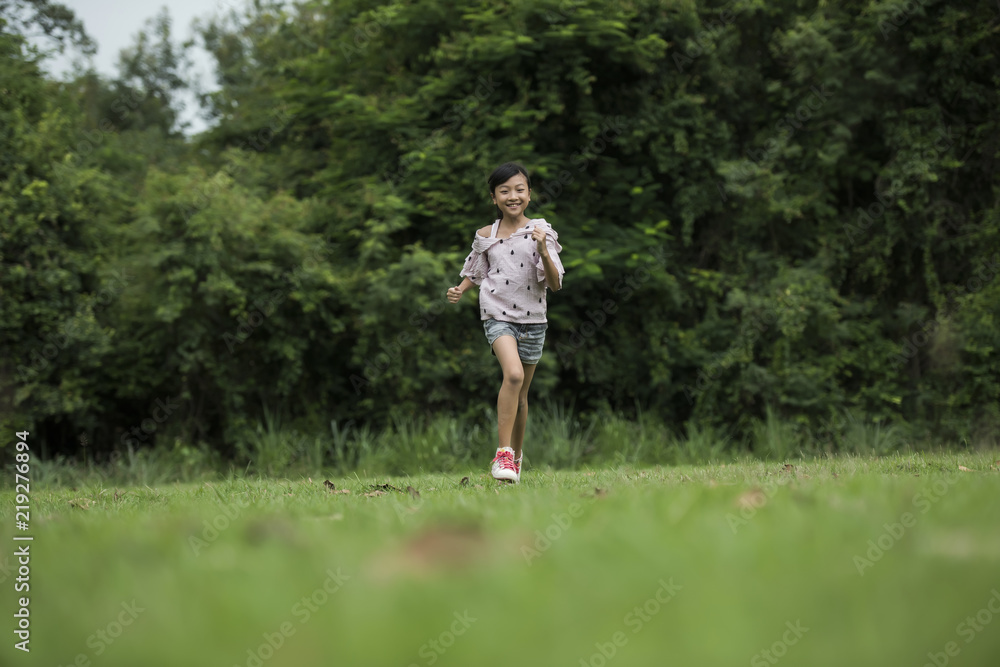 Happy cute little girl running on the grass in the park