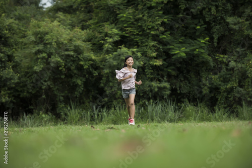 Happy cute little girl running on the grass in the park © Johnstocker