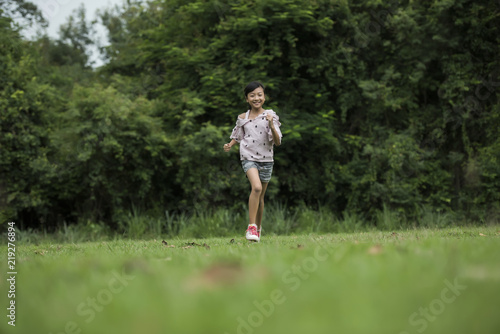 Happy cute little girl running on the grass in the park