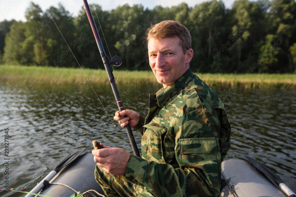 Fisherman fishing rod to fish on the lake with a rubber boat. Fisherman fishing rod to fish on the lake with a rubber boat.
