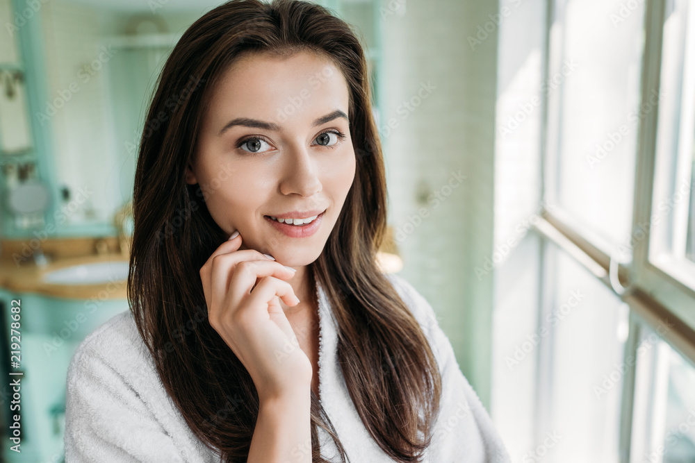 beautiful brunette girl in bathrobe smiling at camera in bathroom beautiful brunette girl in bathrobe smiling at camera in bathroom
