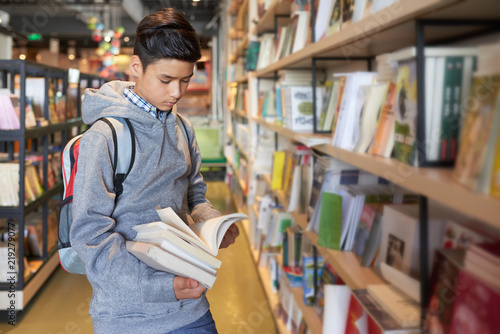 Billede på lærred School boy standing holding books flipping through concentrating