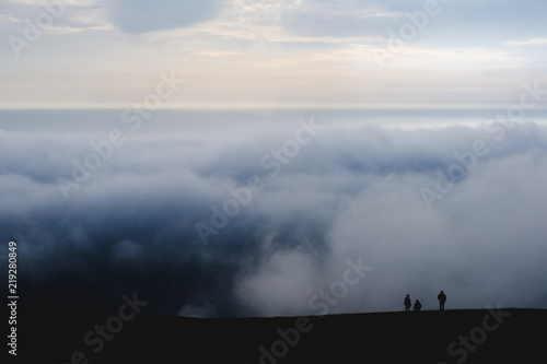 3 Silouat people on the mountain against a background of clouds in the evening. Dark Blue Photo