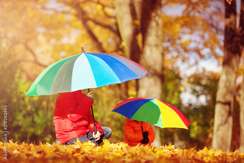 children with umbrellas in beautiful autumnal day