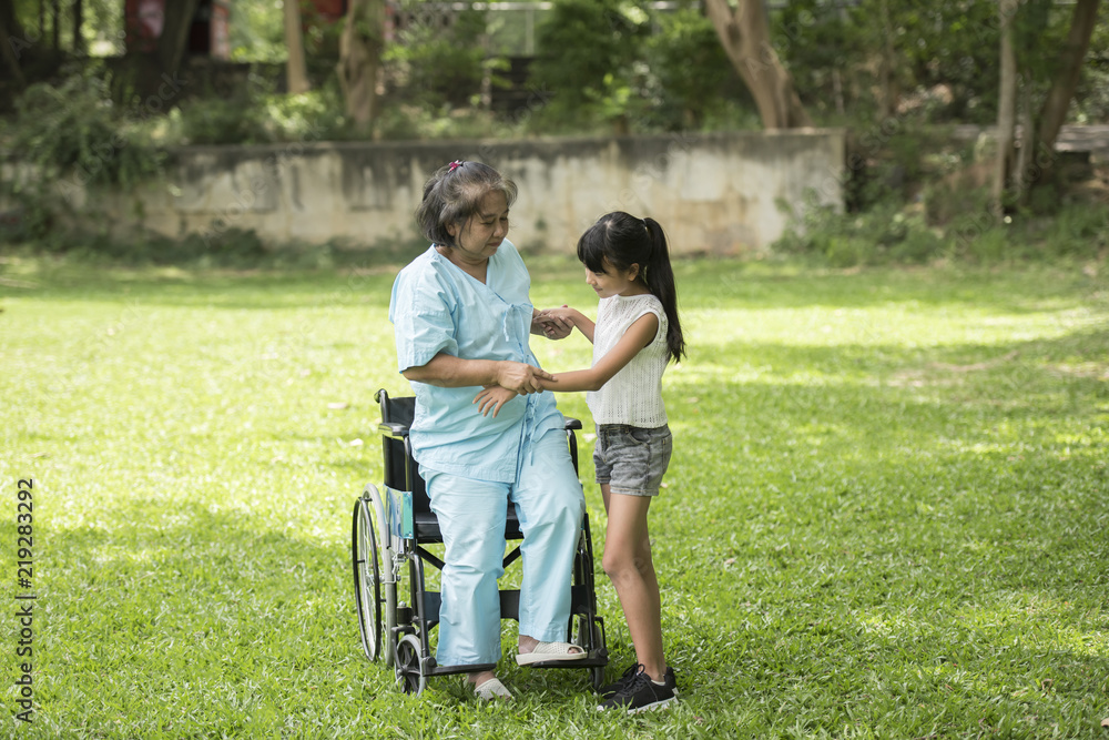 Elderly grandmother in wheelchair with granddaughter in the hospital garden Elderly grandmother in wheelchair with granddaughter in the hospital garden