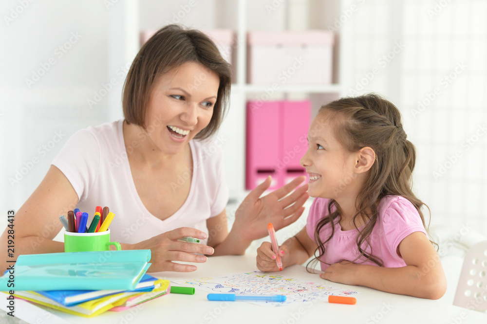 Pretty little girl and her mother doing homework Pretty little girl and her mother doing homework