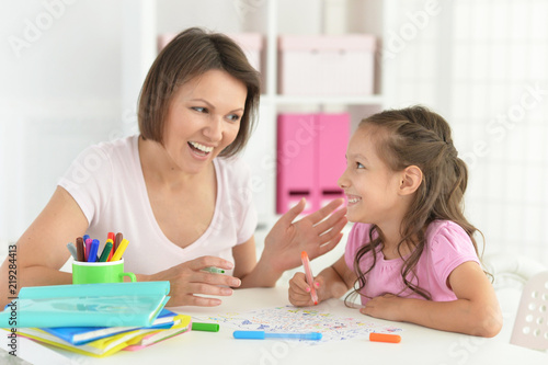 Pretty little girl and her mother doing homework