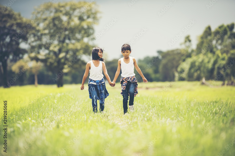 Two little girls hand holding together having fun in the park Two little girls hand holding together having fun in the park