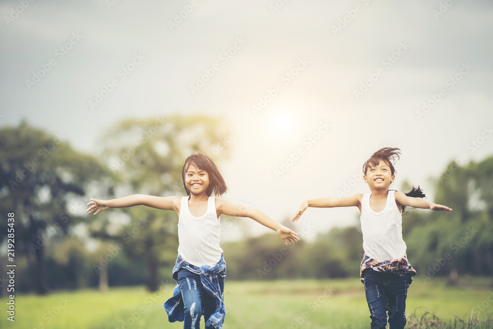Two little cute girls are running on green grass. Best friends. Two little cute girls are running on green grass. Best friends.