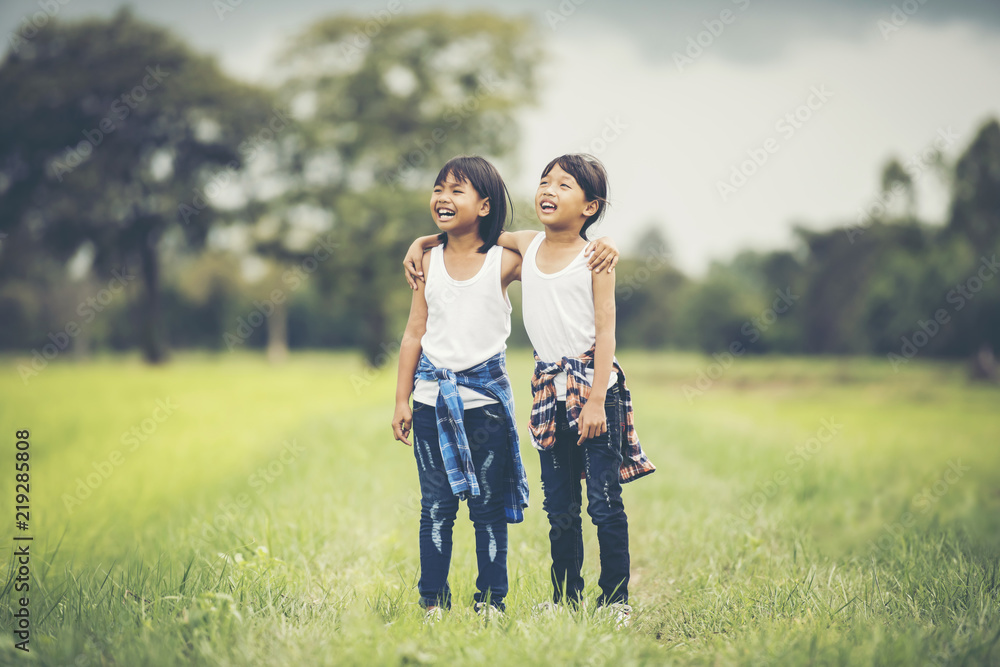 Two little girls hand holding together having fun in the park Two little girls hand holding together having fun in the park