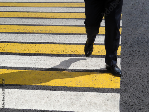 Male legs on the pedestrian crossing. Man in a black business suit crossing the street at a crosswalk, road safety