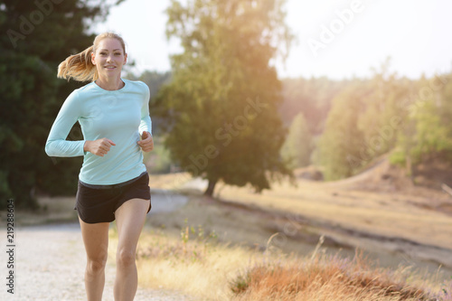 Sporty girl in sportswear jogging, running and training outdoors on a sunny day in summer