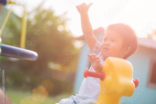 Happy little girl having fun on a playground enjoying a swing ride on a hot summer day in a sunny city park.