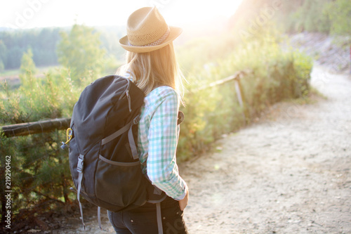 Young woman with backpack hiking through forest and nature on a sunny summer day © Dan Race
