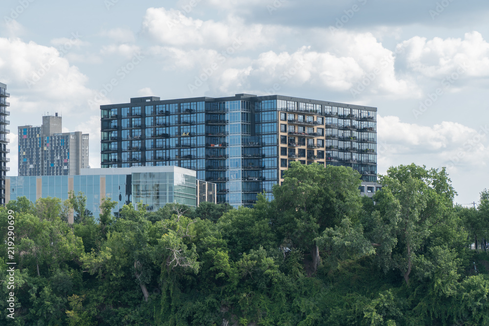 Exterior establishing shot of luxury apartment building real estate along beautiful promenande treeline on outskirts of urban city.