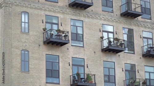 Obraz na płótnie Exterior establishing shot of urban upscale luxury apartment building real estate structure. Large windows from rooms and sliding glass doors onto balconies overlook cityscape w salonie