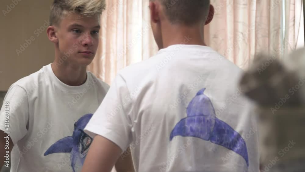 Young man stands near washbasin and big mirror Young man stands near washbasin and big mirror