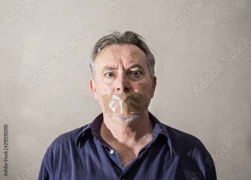uomo con nastro adesivo davanti alla bocca photo