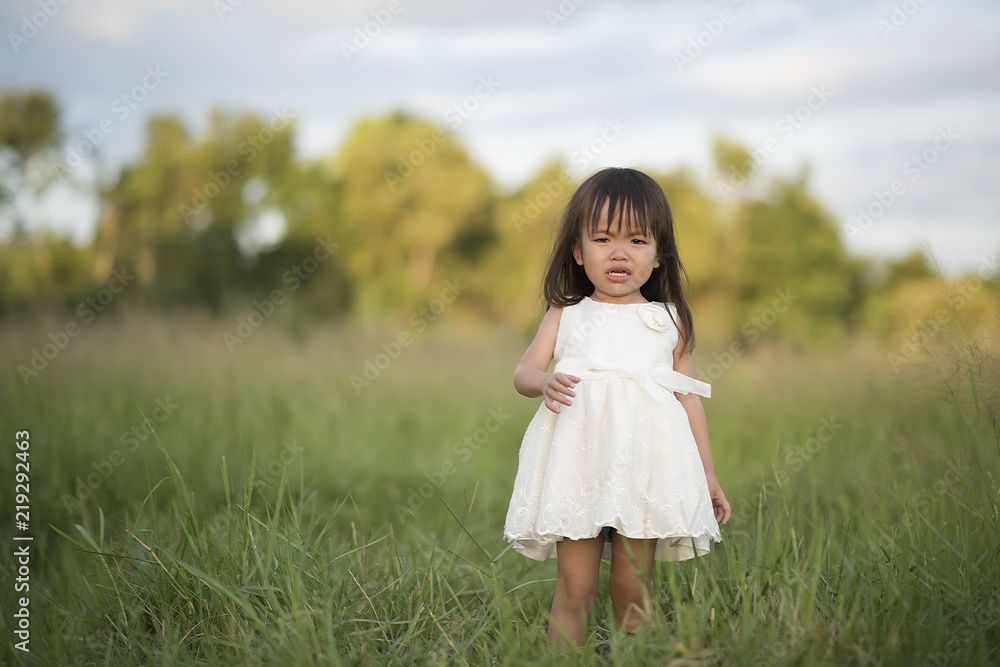 Little girl standing crying in the grass field Little girl standing crying in the grass field