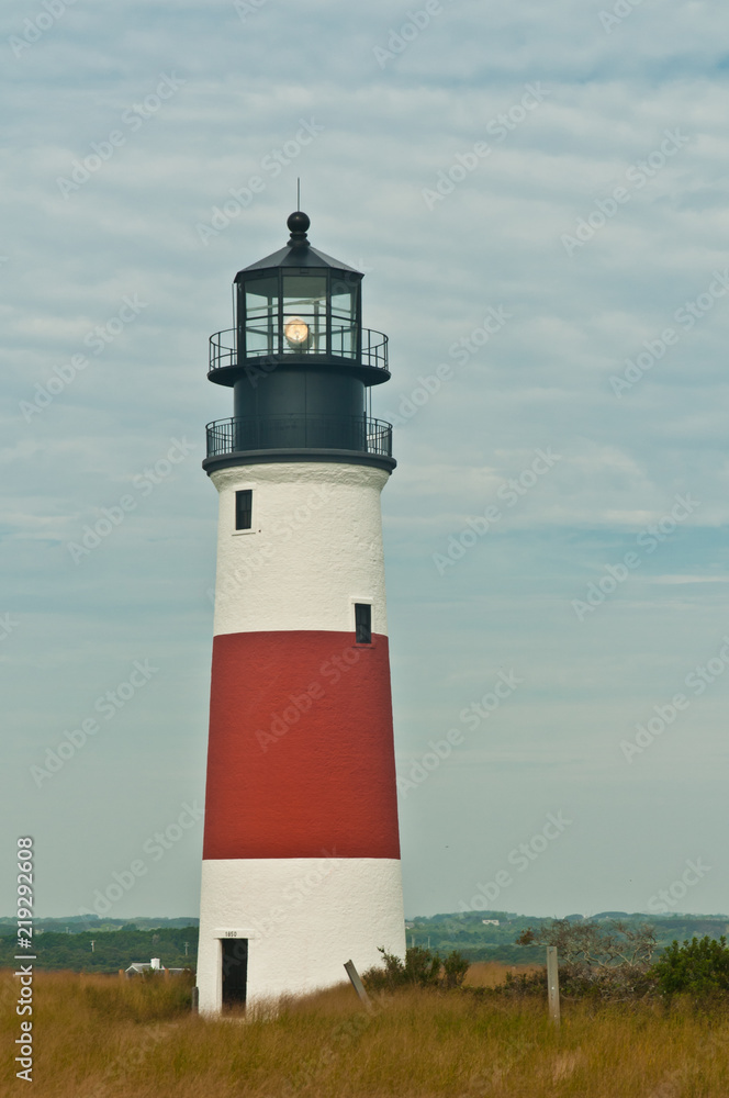 Front view, long distance of an operational lighthouse warning mariners of the shoreline of a barrier island in the north atlantic ocean on a chilly, cloudy, autumn day