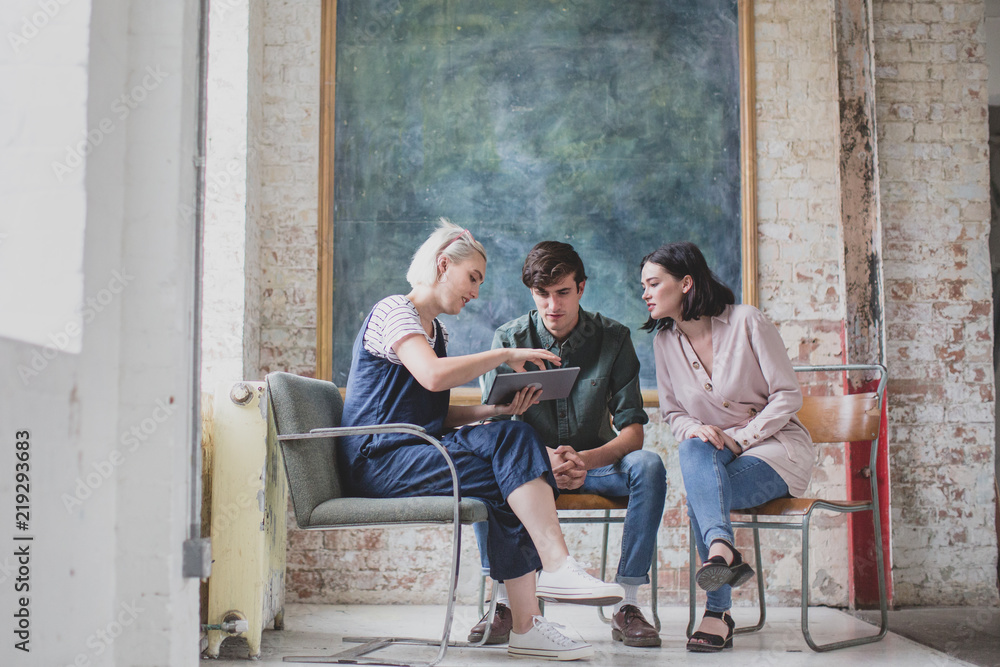 Young adults in a meeting in a creative studio with a digital tablet Young adults in a meeting in a creative studio with a digital tablet