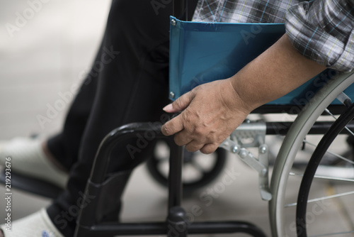 Close-up of senior woman hand on wheel of wheelchair during walk in hospital