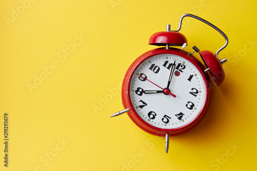 Red vintage alarm clock on yellow background. Alarm clock with place for text.