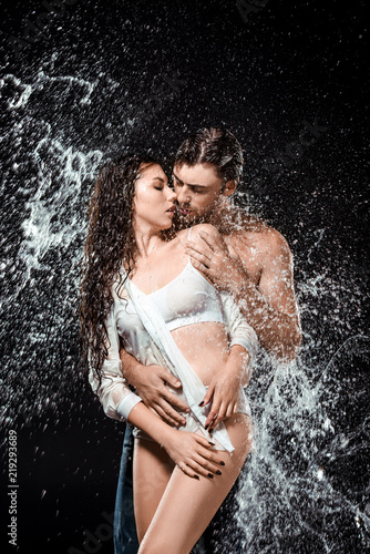 portrait of sexy young couple with water splash isolated on black