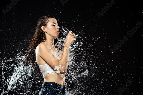 side view of woman with glass of water swilled with water isolated on black