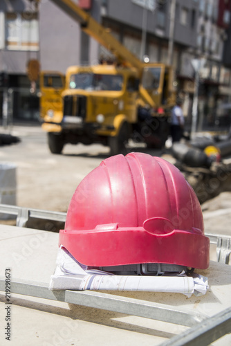 The helmet on the construction plans and buildings in the background