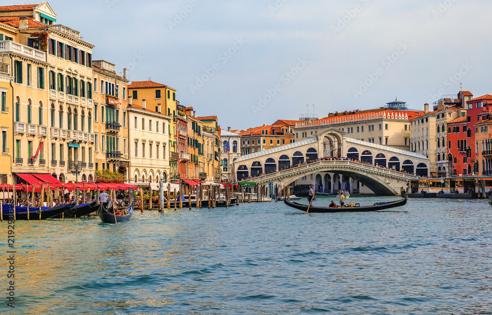 Gondolas and boats by the Rialto Bridge on Grand Canal of Venice Italy