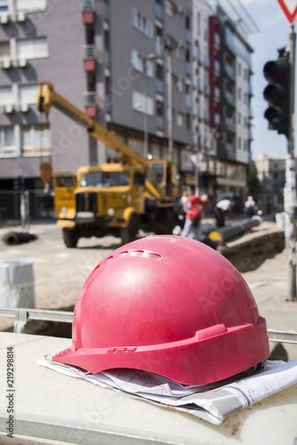 The helmet on the construction plans and buildings in the background