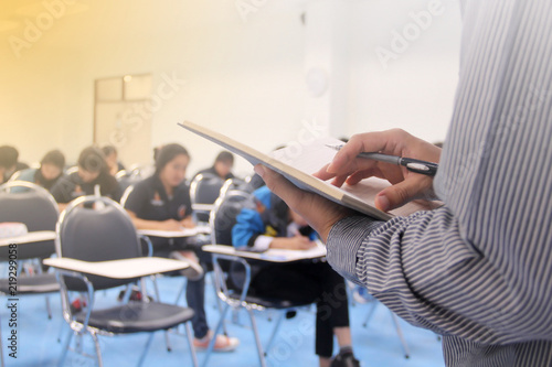 Teacher teach students and background of students during study or quiz, test and exams in large lecture room / University classroom. Students are in uniform classroom educational school.